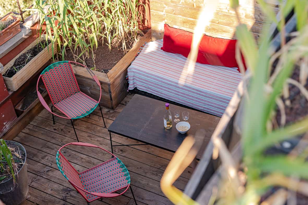 Espace extérieur cosy avec canapé, chaises et table en bois que Séjour Conciergerie gère.